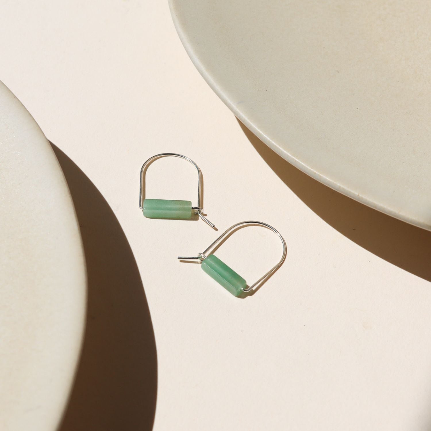 sterling silver arch shaped earrings with aventurine tube beads on a light surface