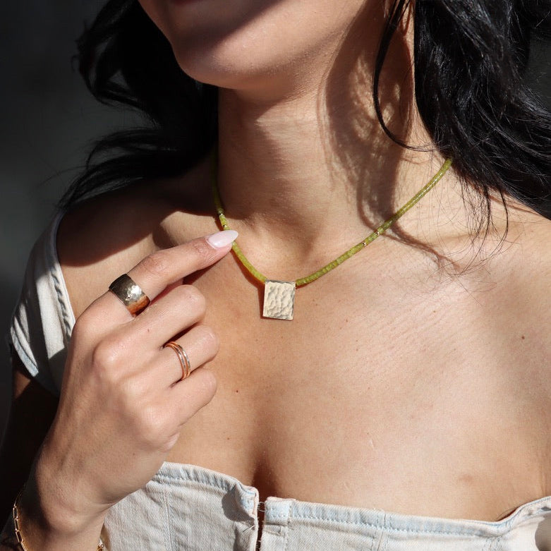model wearing jade beaded necklace with hammered pendant paired with hammered rings