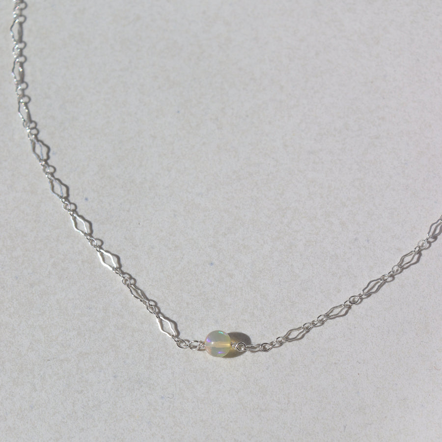 925 Sterling Silver Frankie Opal Necklace laid on a white plate in the sunlight. This Necklace features our Clara chain with the Opal ball bead.