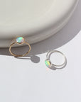 14k gold fill and 925 Sterling silver Sunset ring laid on a white paper on a white jewelry plate. This Ring features a simple hammered band with a 8mm Opal.