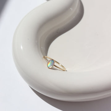 14k gold fill Opal Essence Ring laid on a white plate in the sunlight. This ring features a smooth band with oval opal. These pair great with our stacking rings.