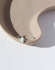 925 sterling silver Opal Essence Ring laid on a white plate in the sunlight. This ring features a smooth band with oval opal. These pair great with our stacking rings.
