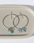 925 Sterling silver Rainbow hoops laid on a gray. These earrings feature a hammered hoop with a hook earring along with a cluster of Opal pebbles.