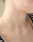 A delicate string of pearl necklace in 14k gold fill photographed on a model
