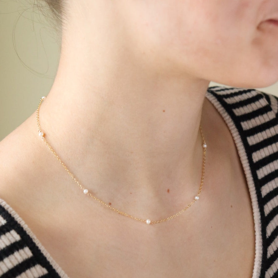 A delicate string of pearl necklace in 14k gold fill photographed on a model