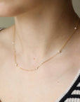 A delicate string of pearl necklace in 14k gold fill photographed on a model at Token Jewelry