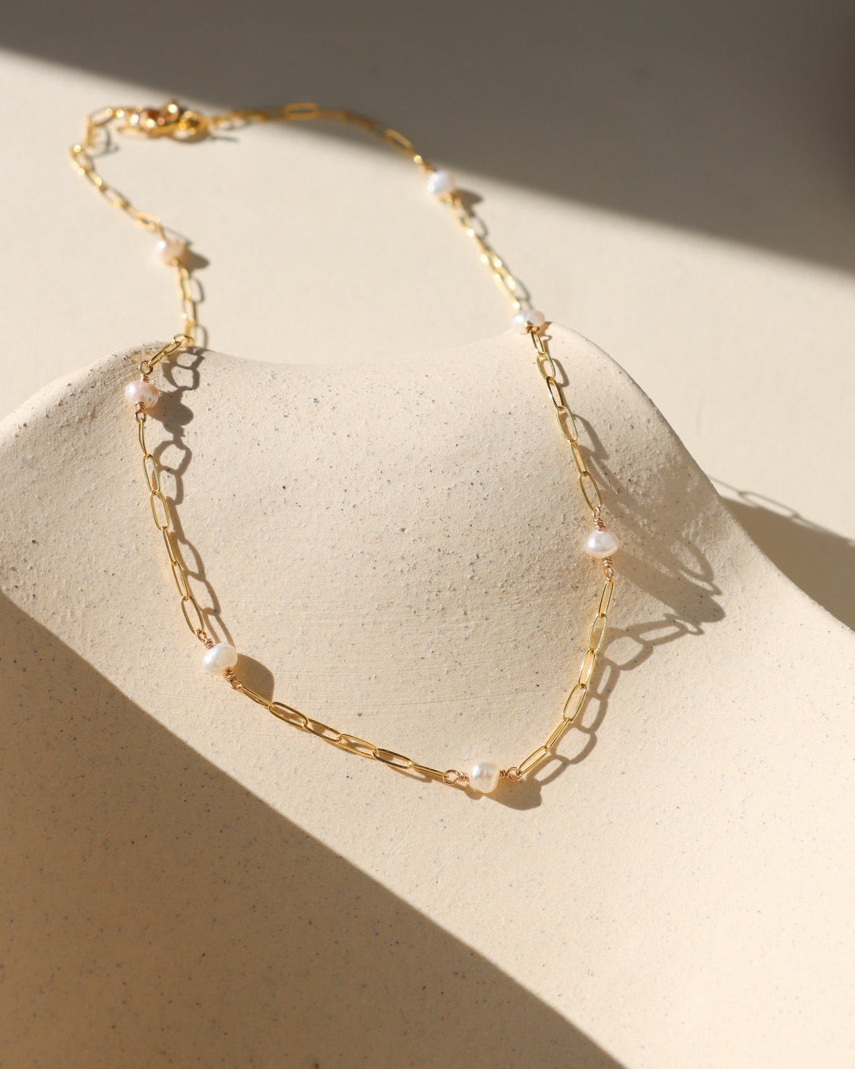 Gold Cosette chain necklace accented with a single lustrous freshwater pearl.
