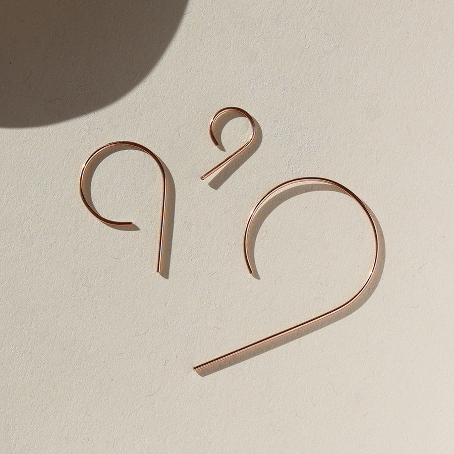 14k rose gold fill "nine" earrings all three sizes laying side by side