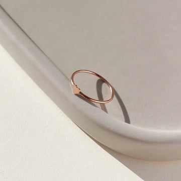 14k rose gold fill ring with a dainty heart, photographed on a ceramic dish