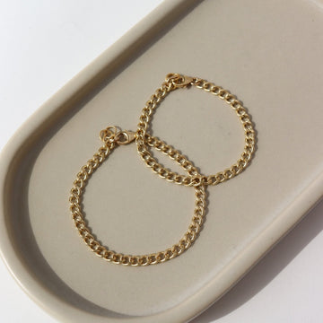 14k gold fill Demi Alexandra Bracelet in adult and children's sizes laid on a gray plate in the sunlight