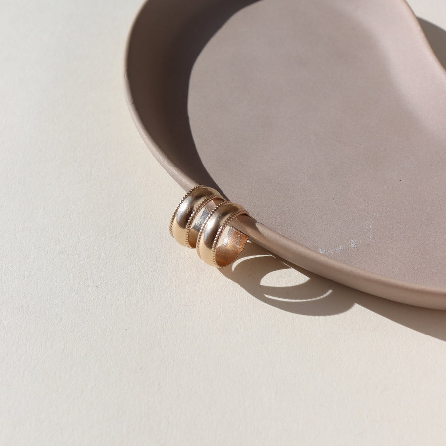 14k gold fill small hoop stud earrings featuring a textured outside band, photographed on a ceramic dish | handmade by Token Jewelry in Eau Claire, Wisconsin