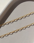 14k gold fill chain laid on a gray plate in the sunlight.