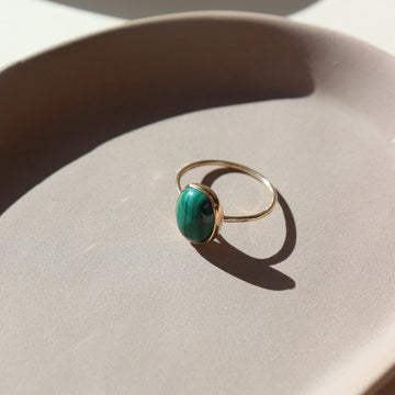 14k gold fill ring with a green malachite stone, photographed on a ceramic dish | handmade by Token Jewelry in Eau Claire, Wisconsin