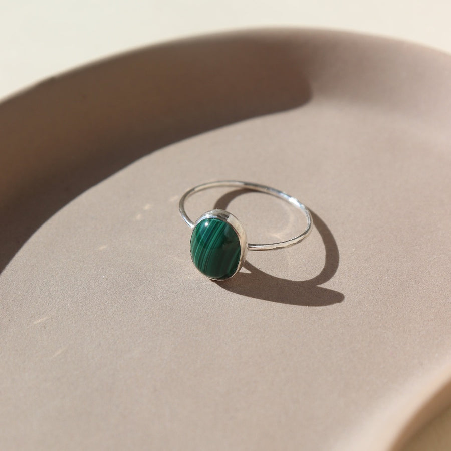 sterling silver ring with a green malachite stone, photographed on a ceramic dish | handmade by Token Jewelry in Eau Claire, Wisconsin
