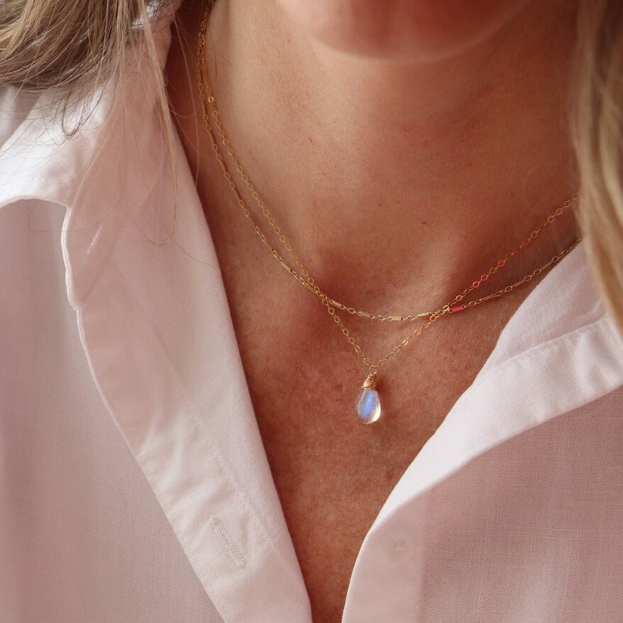 Celine Necklace featuring smooth teardrop moonstone gemstone with blue flash hanging from a dainty 14k gold filled cable chain with spring hook clasp. Fashion Jewelry handmade in by Token Jewelry in Eau Claire, WI  Edit alt text