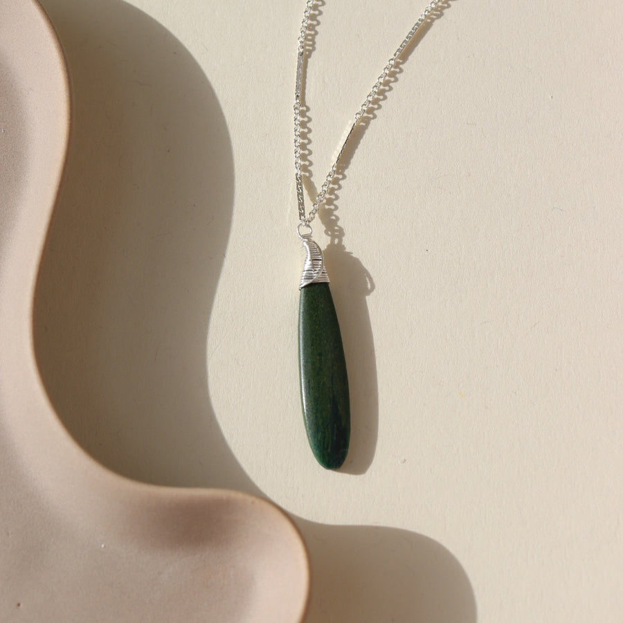 Token Jewelry sterling silver Sailor chain necklace with a long green malachite stone, photographed on a ceramic dish