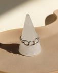 925 Sterling Silver chain ring that features a Alexandra chain along with the la mer chain set on top of a ring holders set on top of a tan ceramic dish
