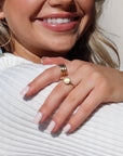 Model wearing 14k gold fill Sunset Ring on her middle finger along with other token Jewelry. This Ring features a simple hammered band with a 8mm Opal.