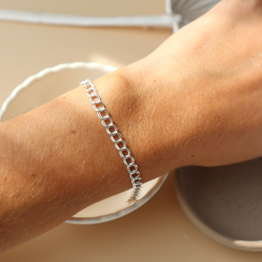 Model wearing 925 Sterling Silver Double link bracelet laid on top of a white clay plate. Jewelry is handmade in Eau Claire Wisconsin. Hypoallergenic jewelry made to live in.
