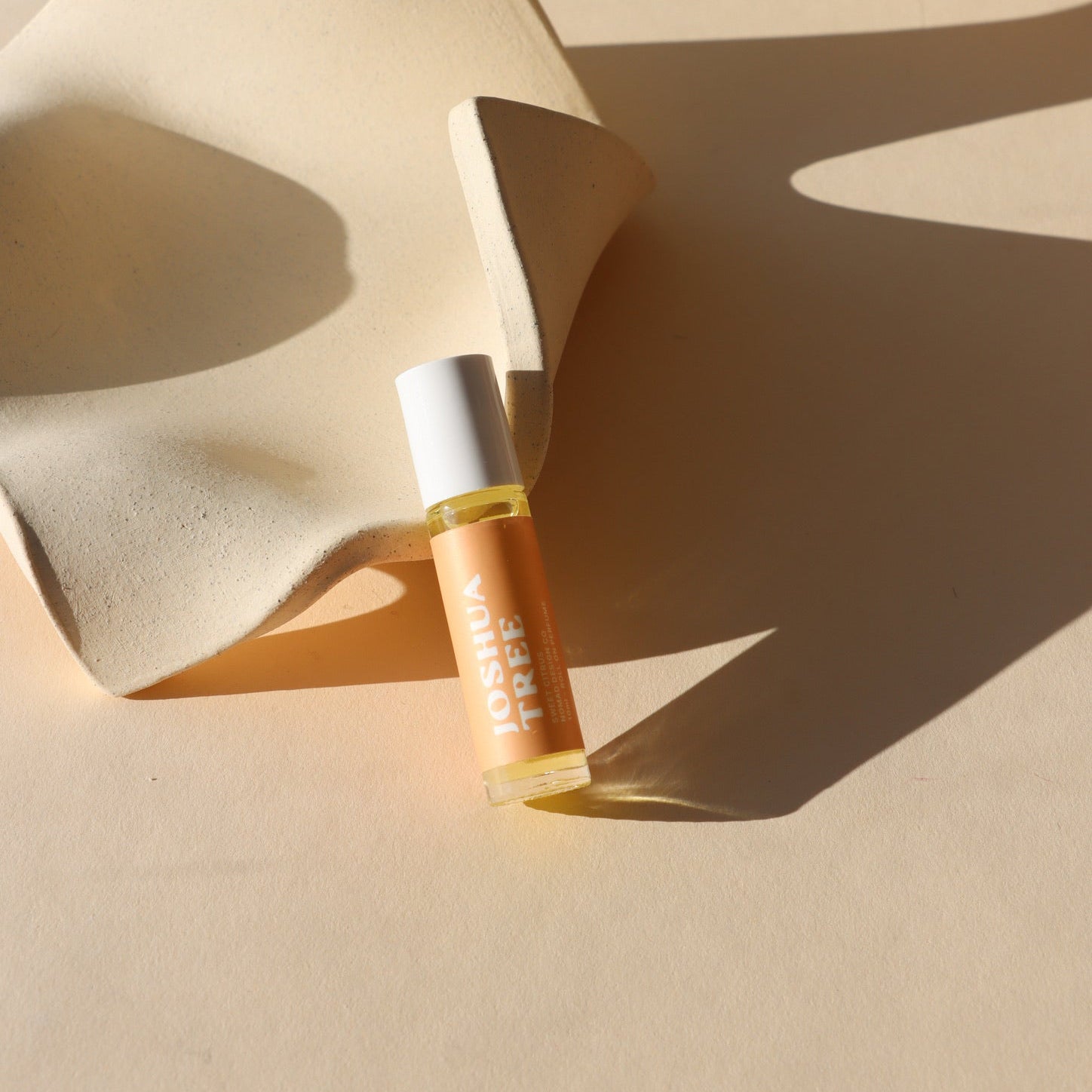 peach colored perfume roller near a dish in the sunlight - scent Joshua Tree