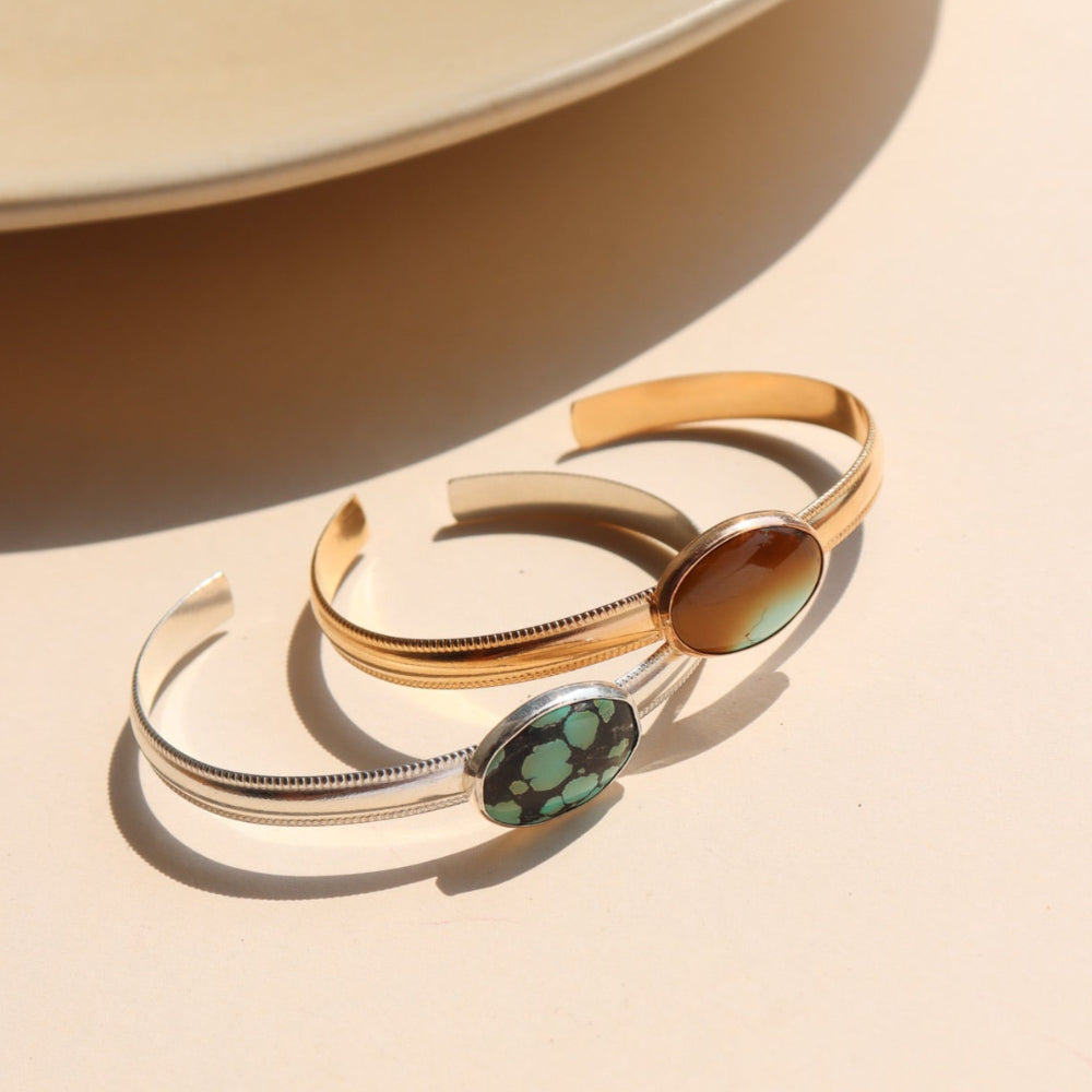 A sterling silver and 14k gold fill smooth cuff with a 13x18mm turquoise stone set at its center