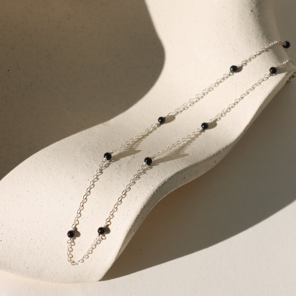 The Lennox Chain features smooth black tourmaline gemstones along a delicate cable chain—crafted in gold fill or sterling silver for balance and protection