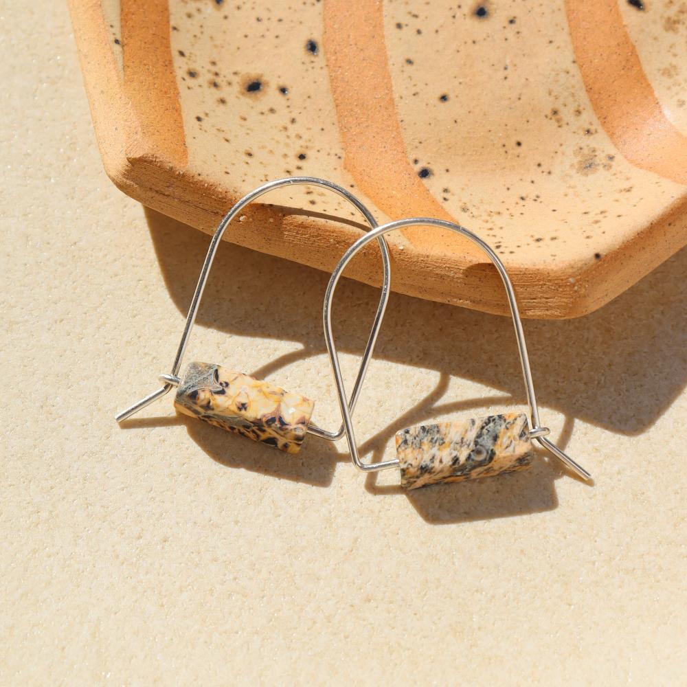 sterling silver hand shaped arch earrings with leopard jasper stones on a light background