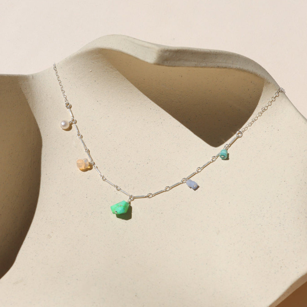 sterling silver chain necklace with gemstone charms on a light surface