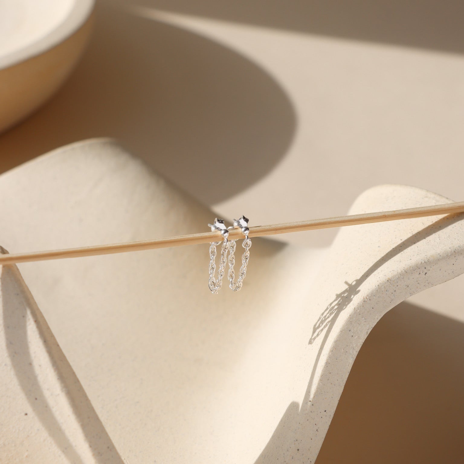 chain stud earrings in sterling silver hanging  in the sunlight