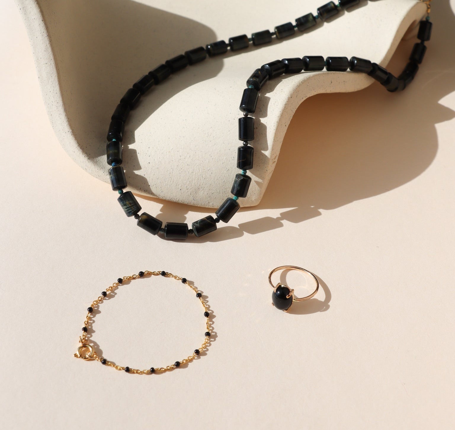 Jewelry set including a necklace, bracelet, and ring on a beige surface