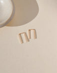 14k gold fill mini staple shaped earrings laid by small dish in the sunlight