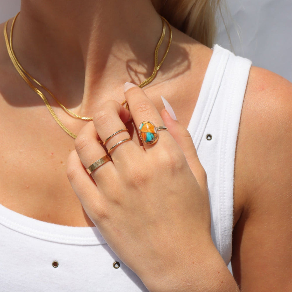 Model wearing Mojave Turquoise Ring with a blend of turquoise, spiny oyster shell, and copper set on a textured hand-hammered band.