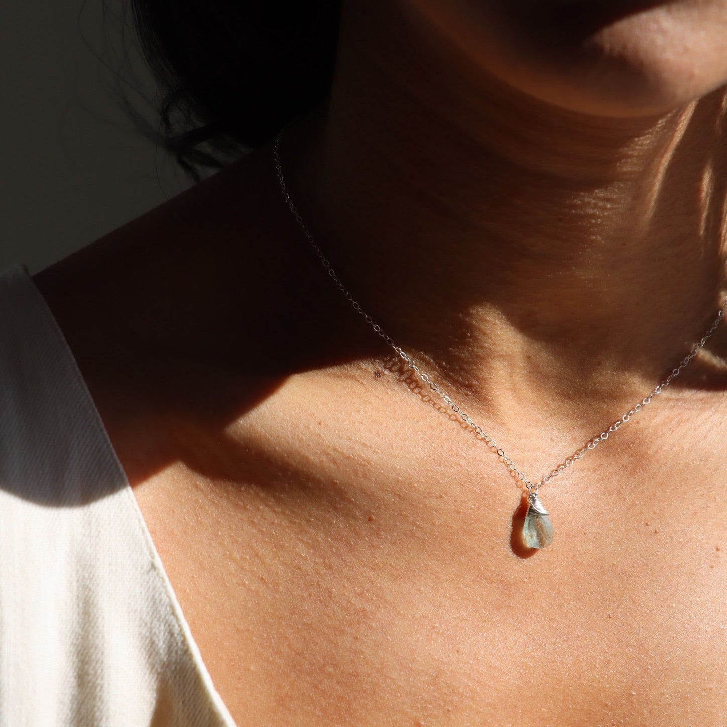 model wearing sterling silver dainty chain necklace with teardrop aquamarine stone