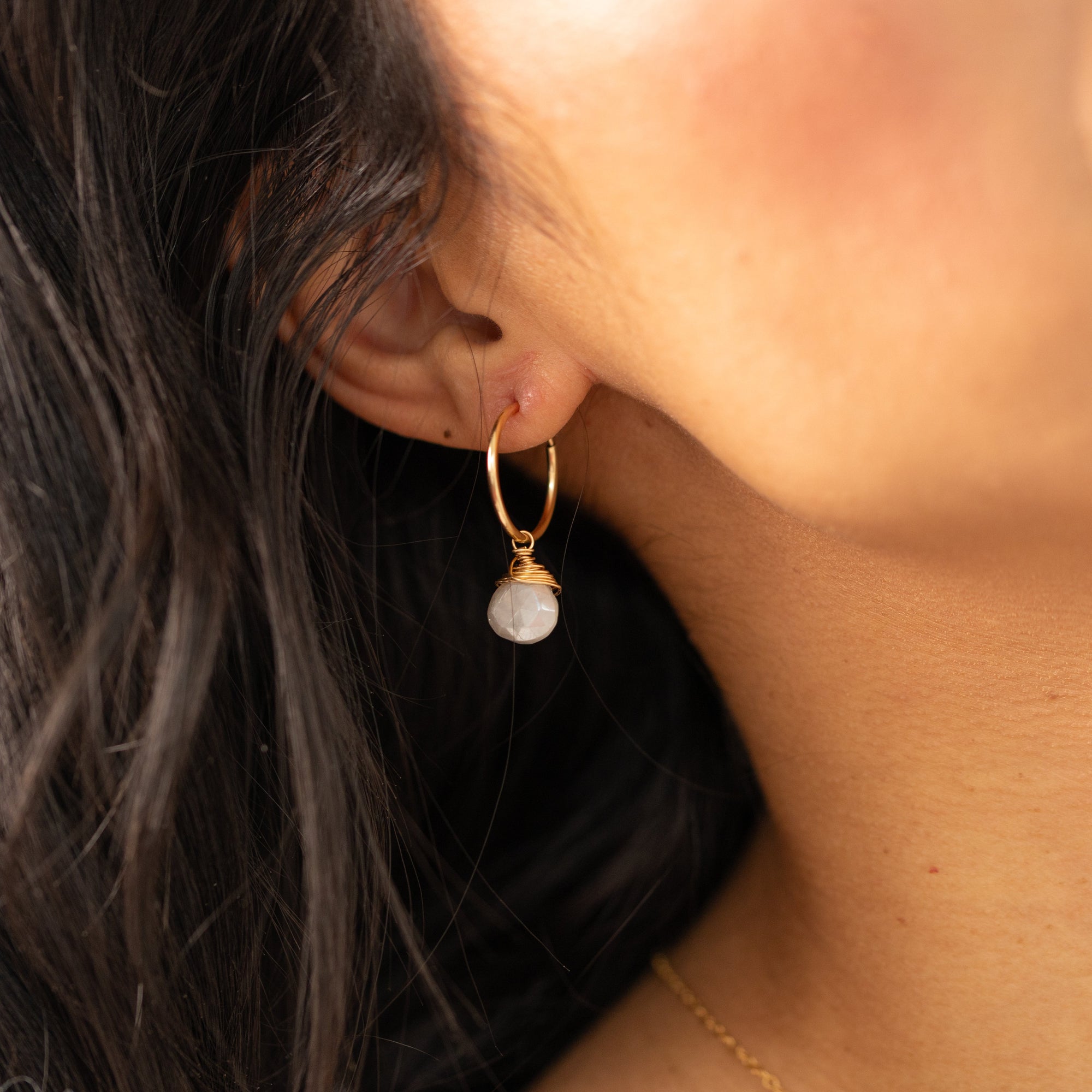 Gold hoop earrings featuring iridescent moonstone charms with soft, shimmering hues.
