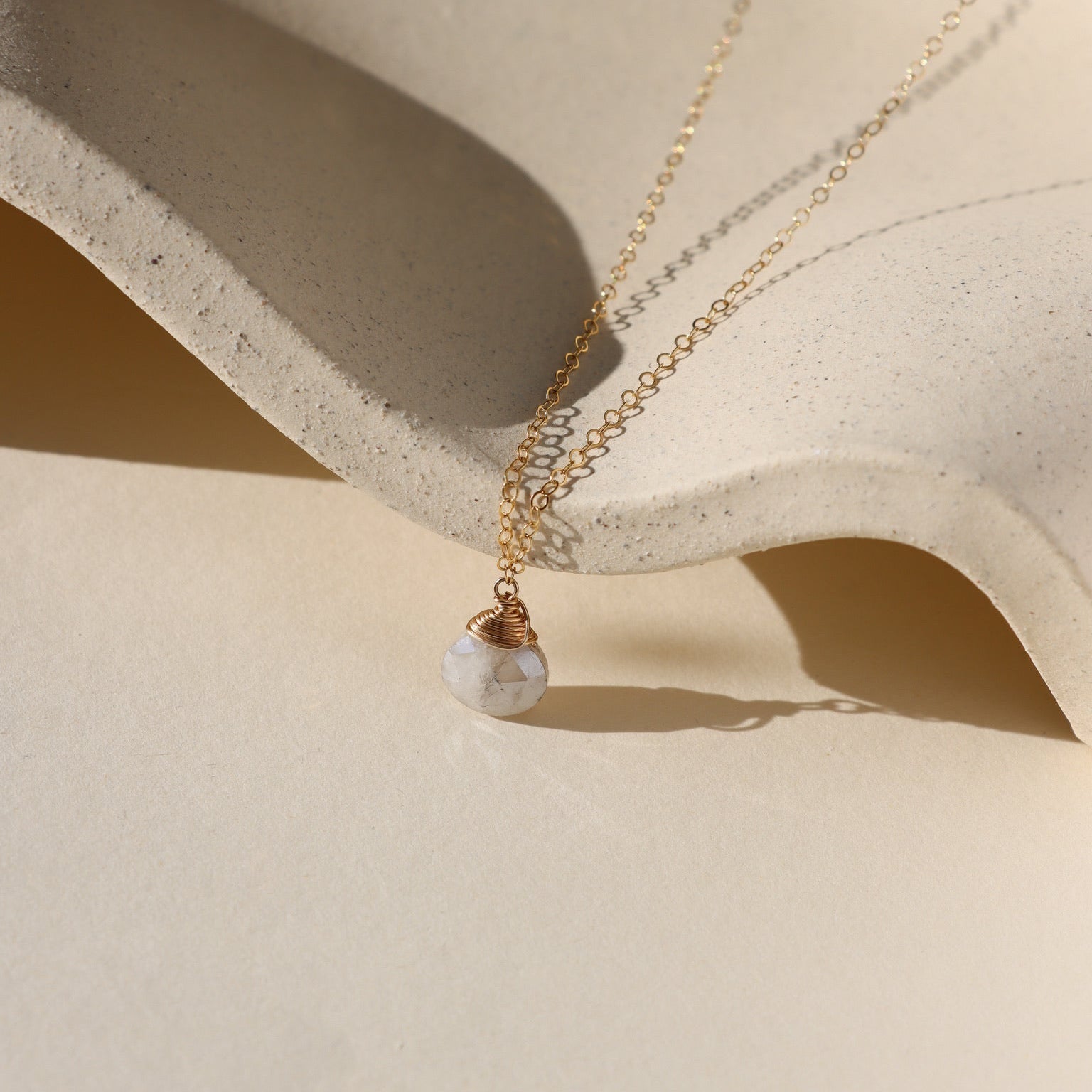 Delicate gold necklace featuring a shimmering oval moonstone pendant with iridescent hues.