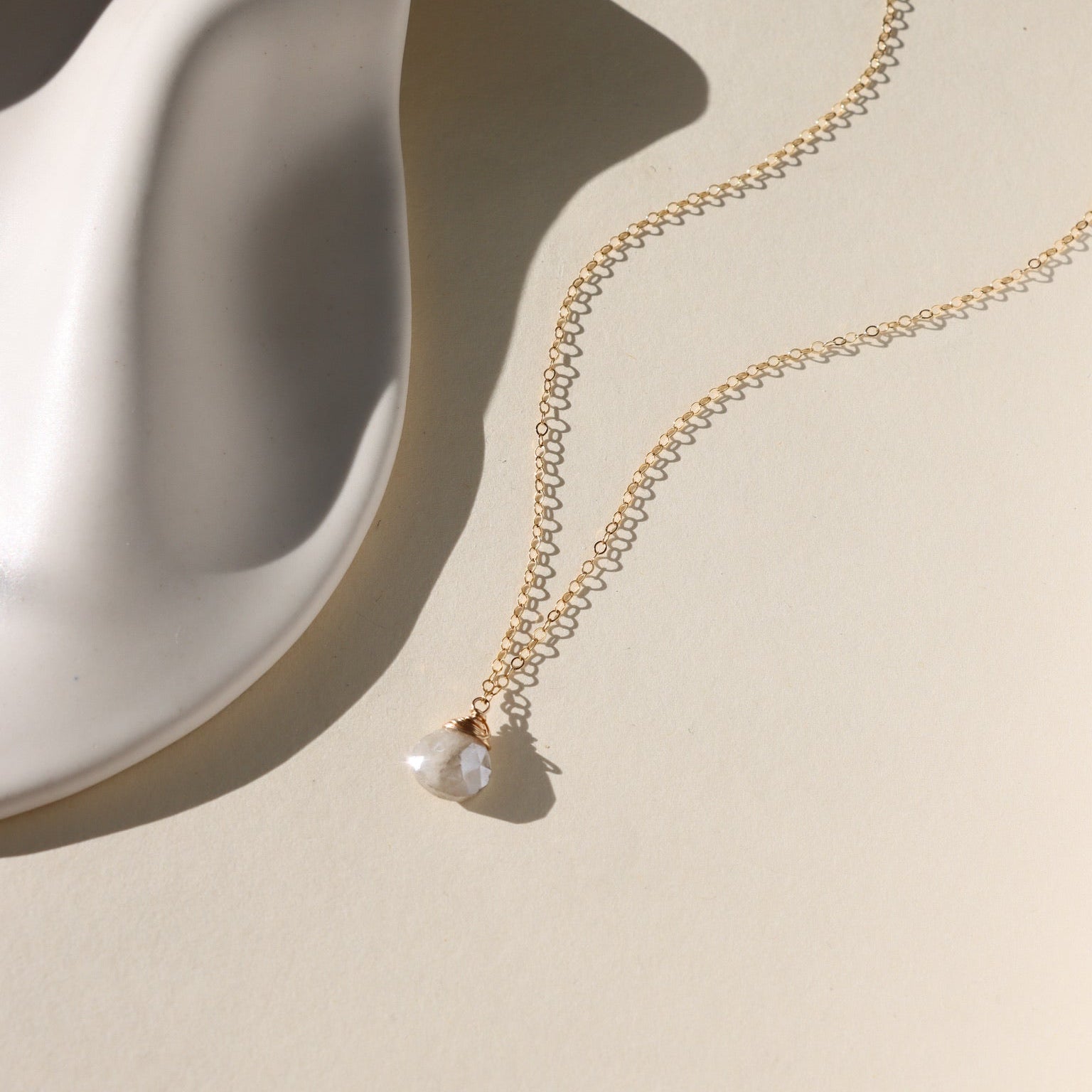 Delicate gold necklace featuring a shimmering oval moonstone pendant with iridescent hues.