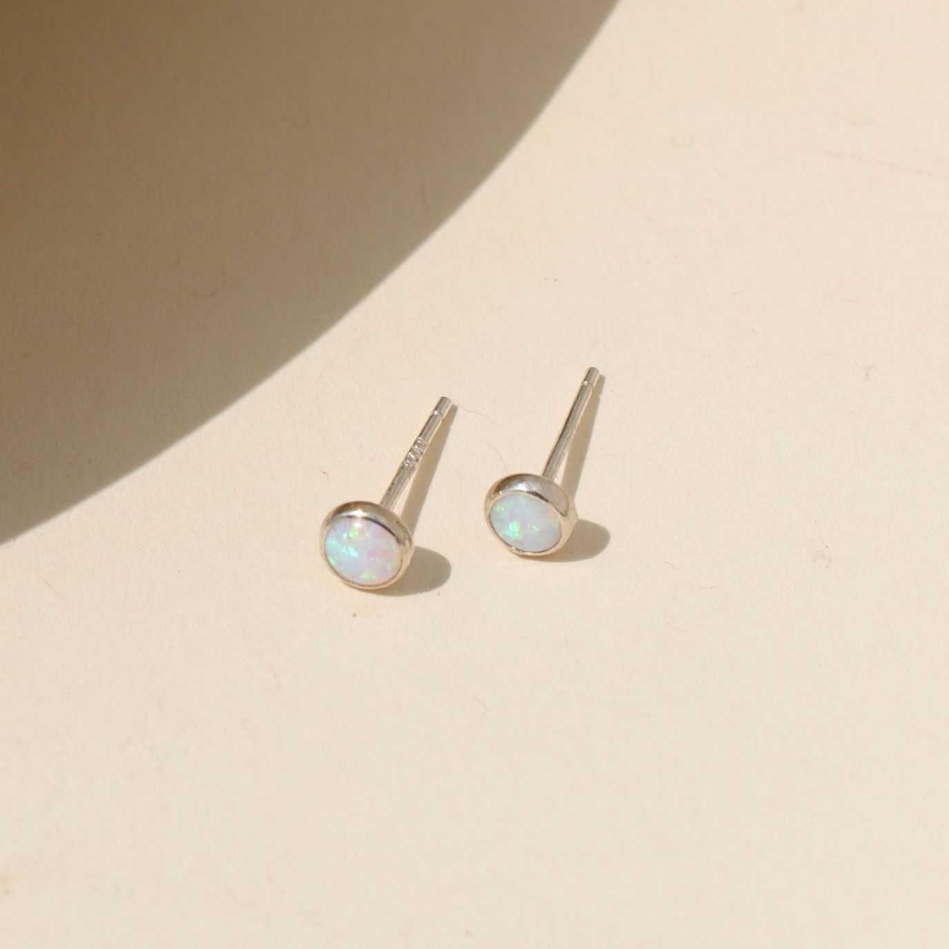 sterling silver stud earrings with round opal stones in the sunlight