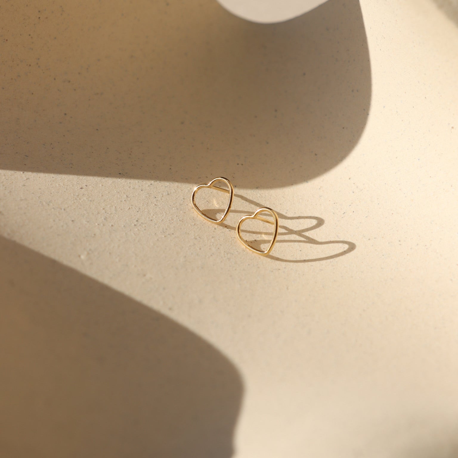 14k gold fill open heart studs on a light background