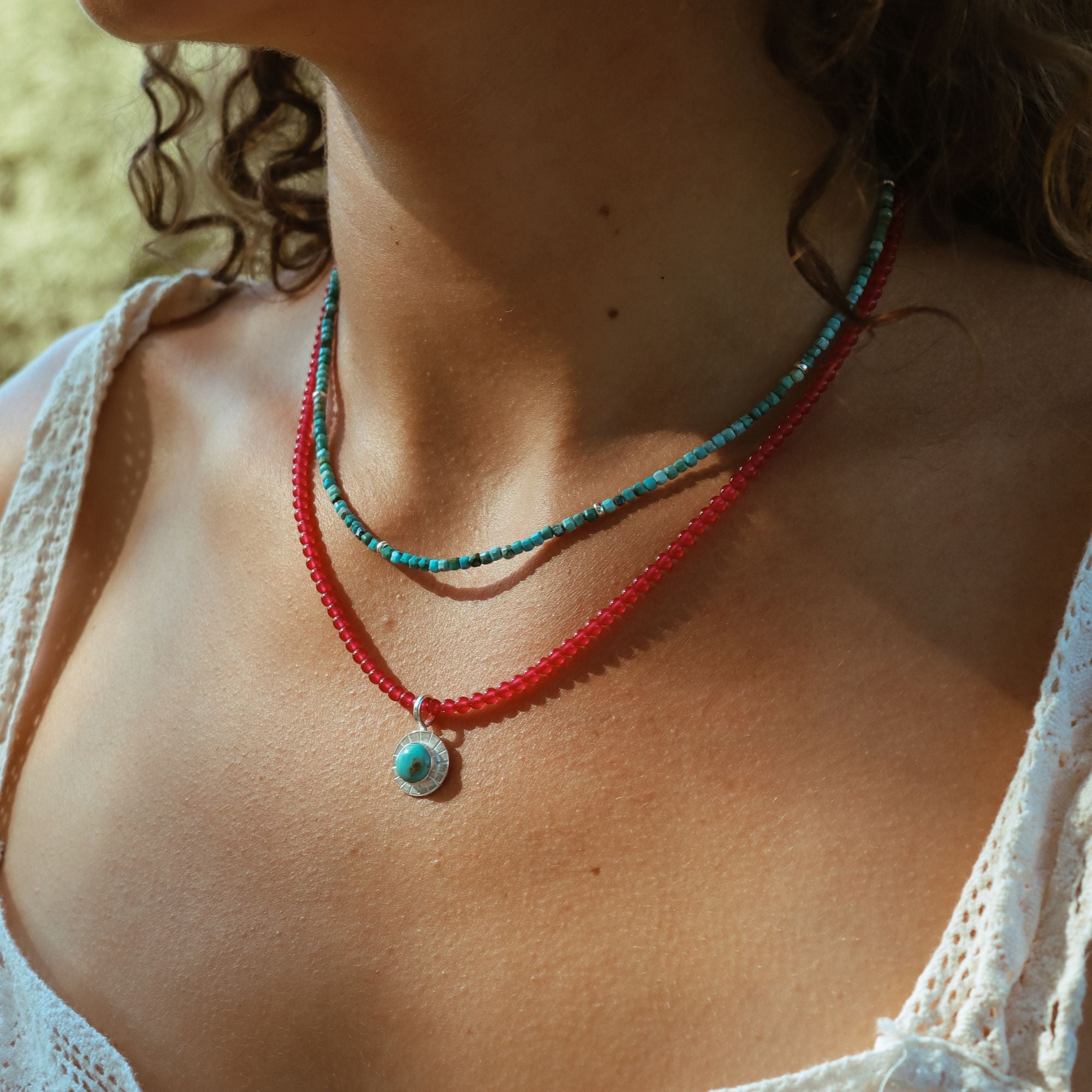 model wearing turquoise and ruby beaded necklaces with round turquoise pendant