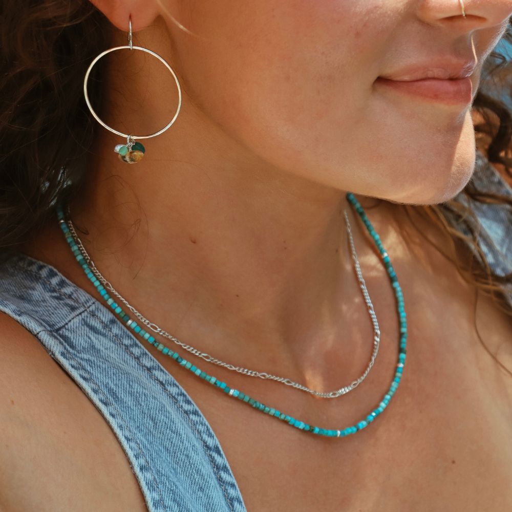 model wearing sterling silver hoops with gemstones and beaded turquoise necklace