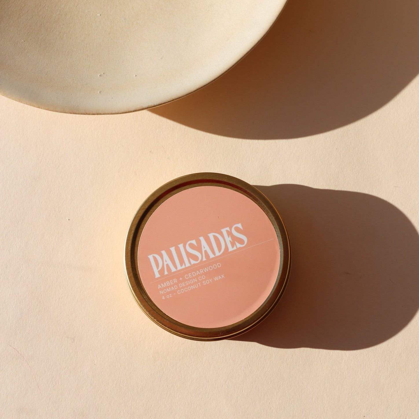 peach colored candle tin on a light background - scent is palisades