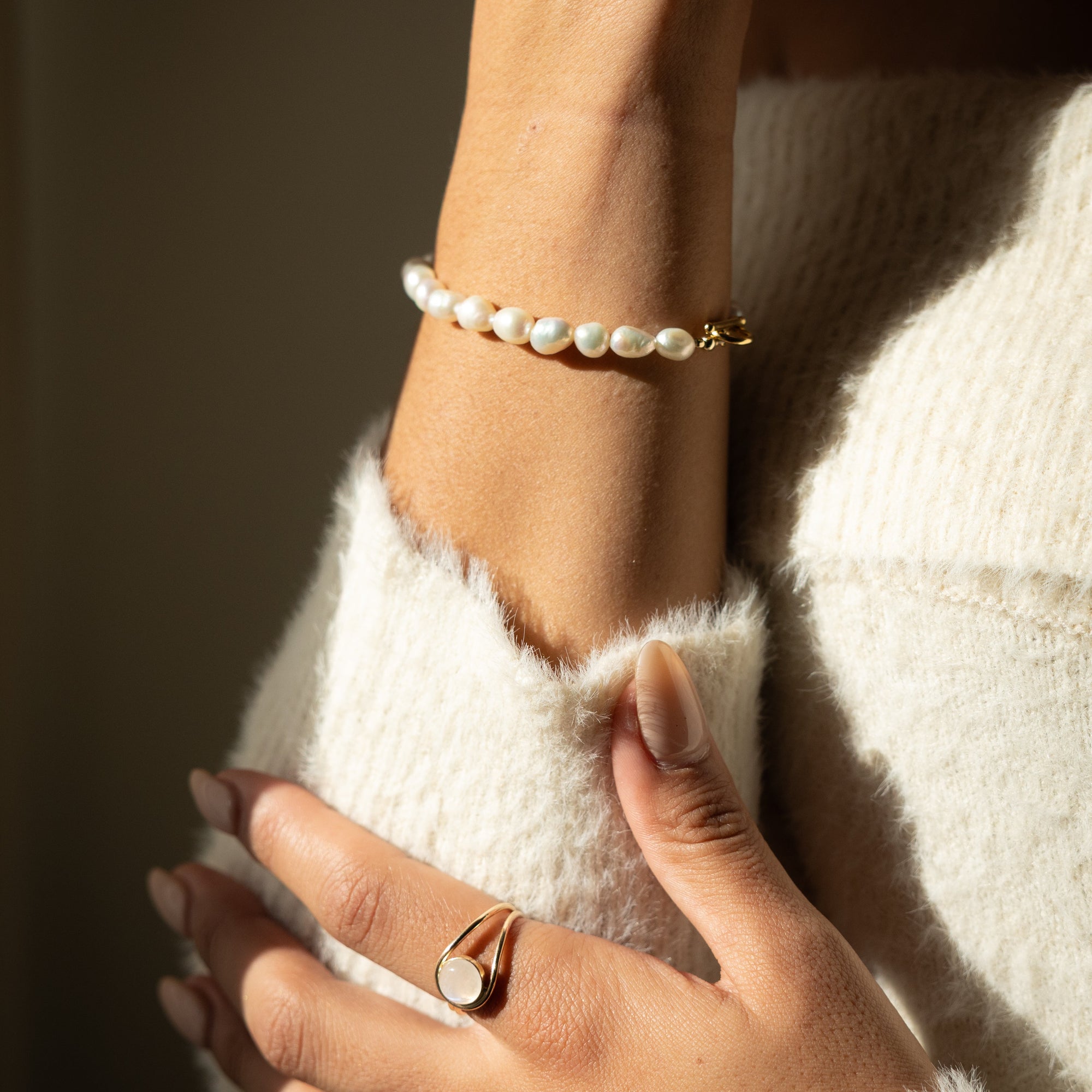 Gold toggle bracelet featuring a strand of lustrous freshwater pearls and a bold circular toggle clasp.