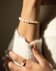 Gold toggle bracelet featuring a strand of lustrous freshwater pearls and a bold circular toggle clasp.