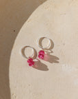 pink topaz charm in sterling silver shown on a simple sterling silver hoop earring in the sunlight