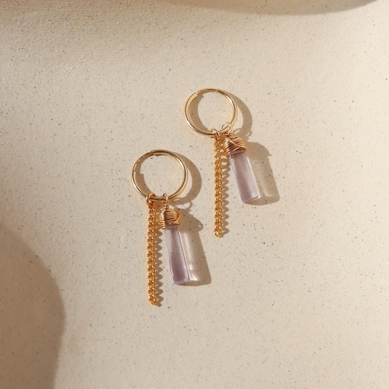 14k gold fill hoop earrings with pink amethsyt charms and sterling silver chain on a light background