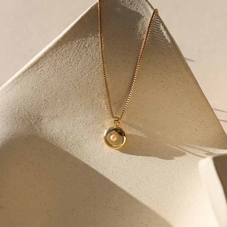 14k gold fill chain with a locket pendant with a pink pearl on the cover with a light background