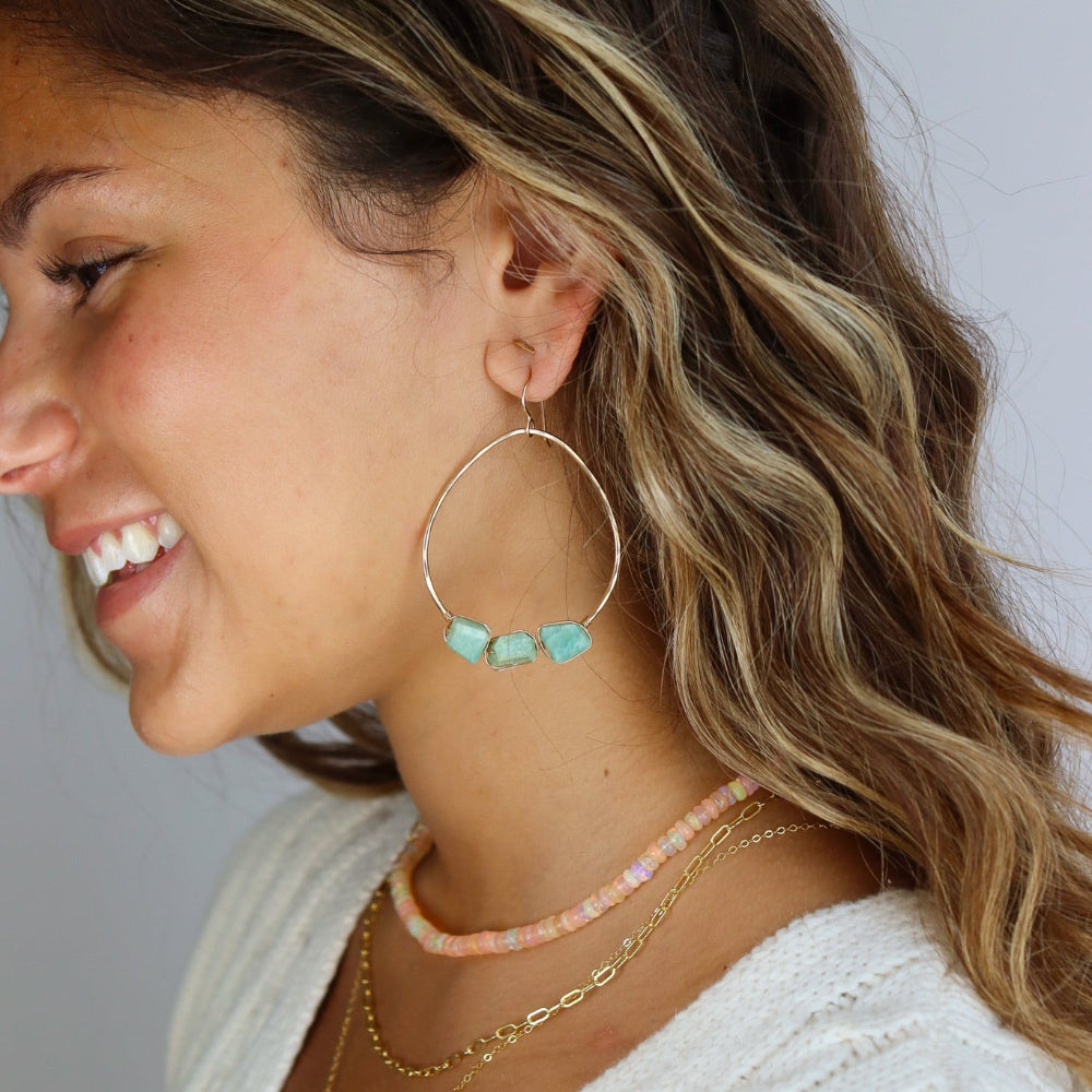 A model wearing a 1.75 wide 14k gold fill wire hoop with three amazonite gemstones wire wrapped at the bottom of each earring. 