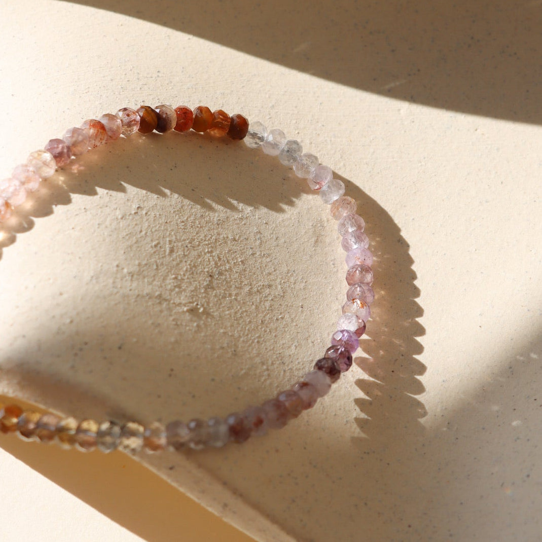 Beaded bracelet on a textured beige surface with soft shadows