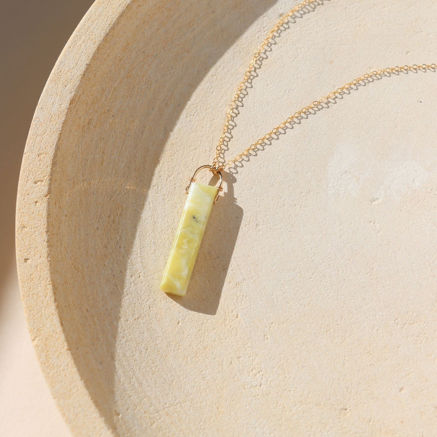 14k gold fill chain necklace with rectangle serpentine pendant on a light dish