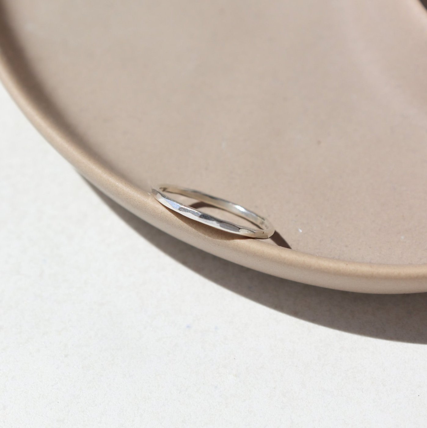 sterling silver skinny ring laid on a tan plate